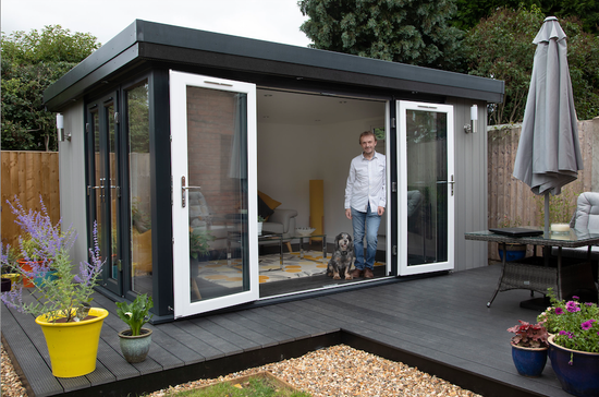 A man standing in front of a garden shed.