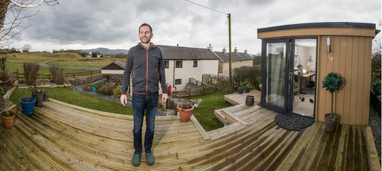 A man standing on a deck in front of a house.