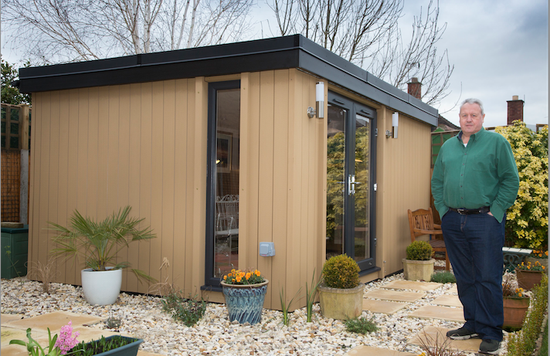 A man standing in front of a garden shed.