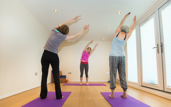 Three women doing yoga in a garden room in north wales