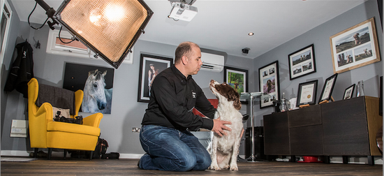 A man kneeling on the floor next to a dog.